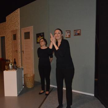 Dwie kobiety stojące na scenie. Jedna używa języka migowego