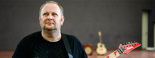 Krzysztof Misiak z gitarą patrzący w górę