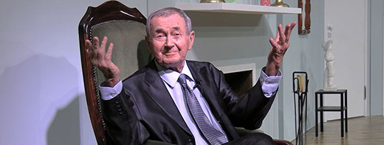 Dyrektor Marek Mokrowiecki siedzący na fotelu z uniesionymi dłońmi
