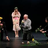 Kobieta stoi, trzej mężczyźni klęczą z kwiatami
