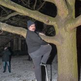 Mężczyzna wchodzi na drzewo po drabince